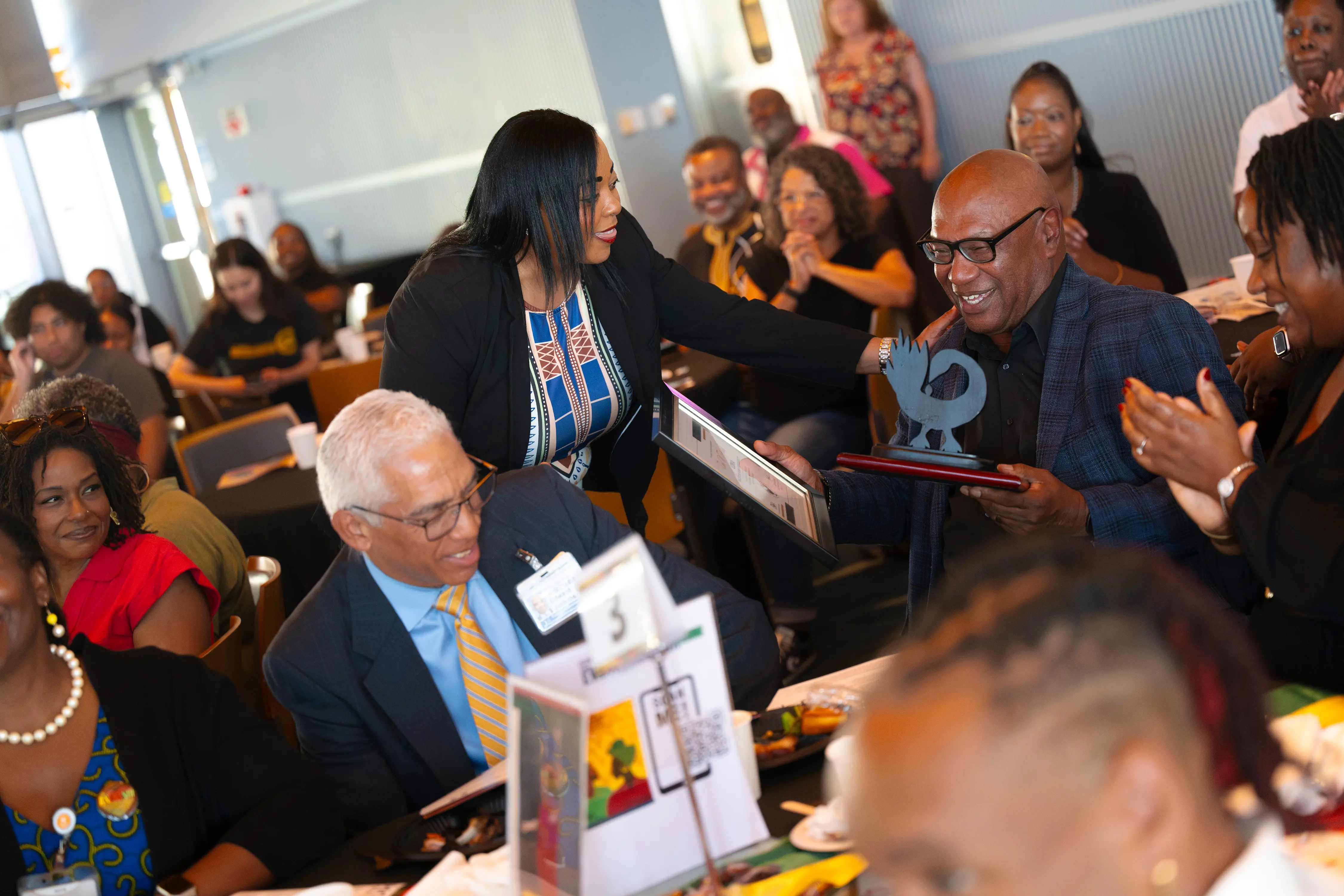 A person presents an award to someone sitting down