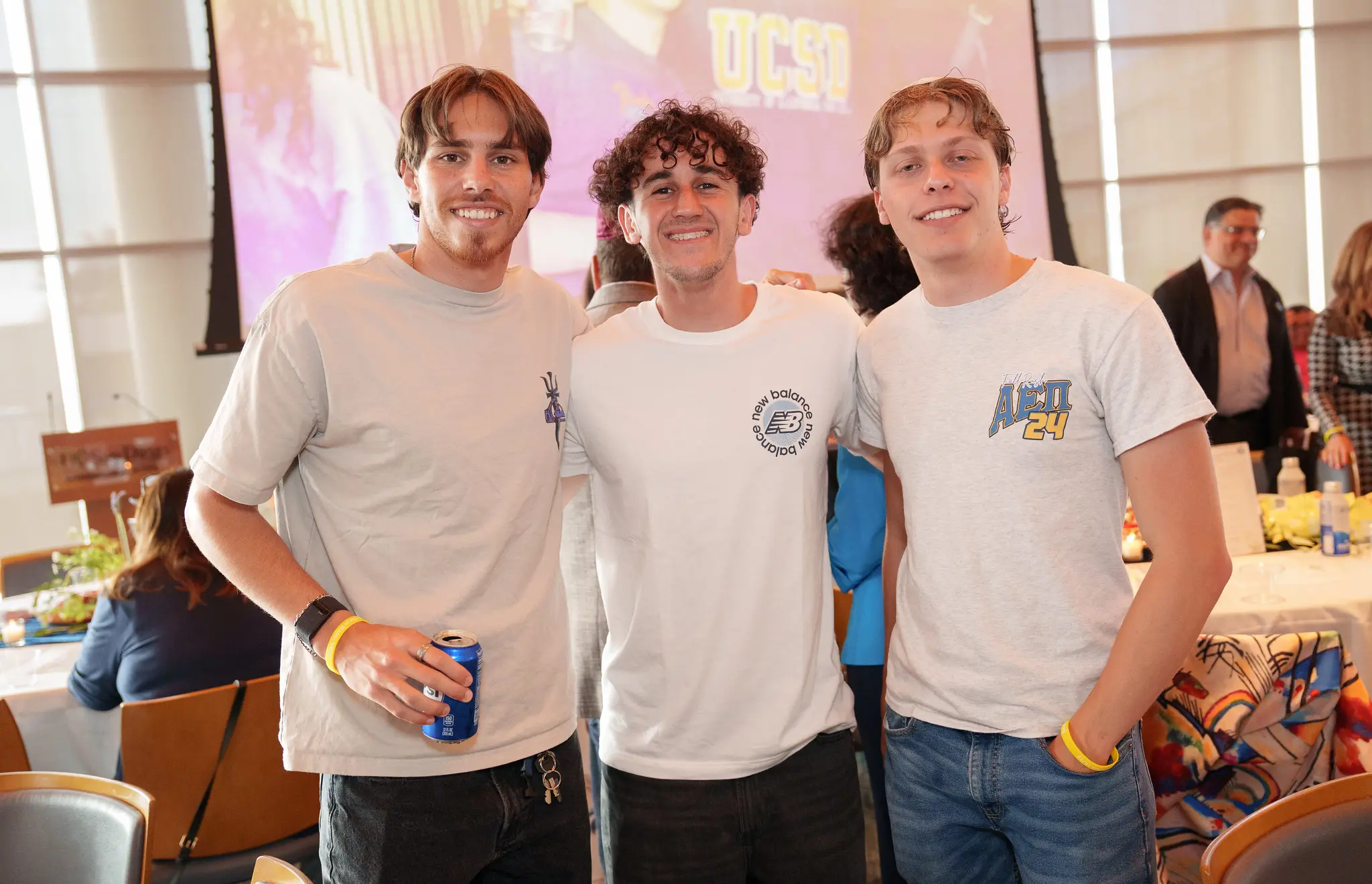 Three students in white t-shirts smile at camera
