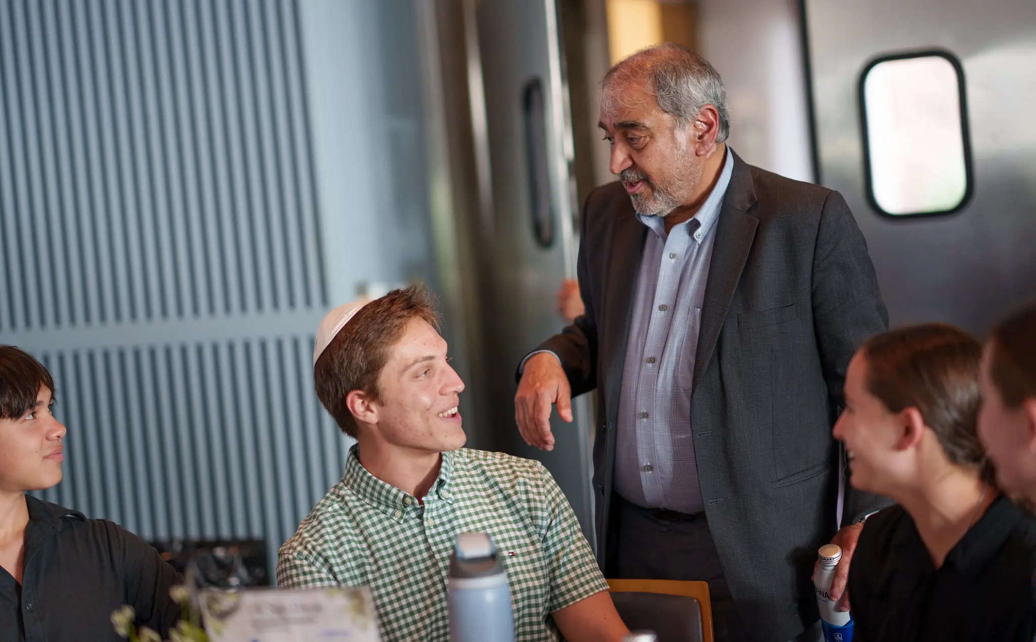 Older man smiles at student sitting down