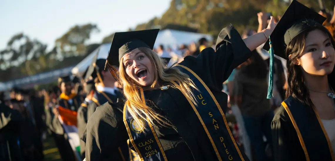 Girl in cap and gown with arms in air