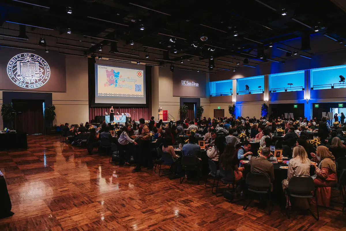 Wide-angle shot of a large crowd sitting at tables in a conference room