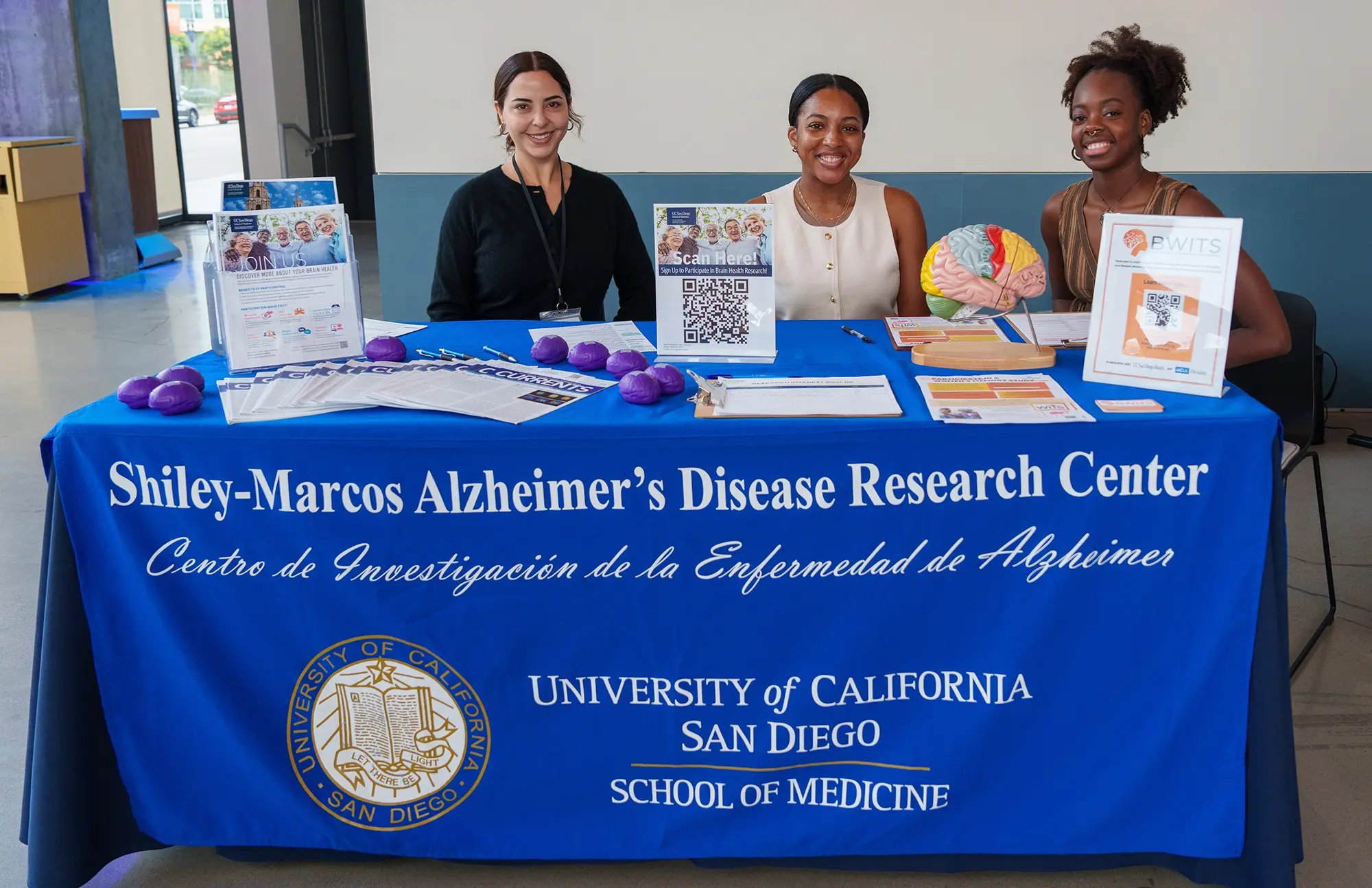Booth at symposium with three females representing the Shiley-Marcos Alzheimer Disease Research Center.