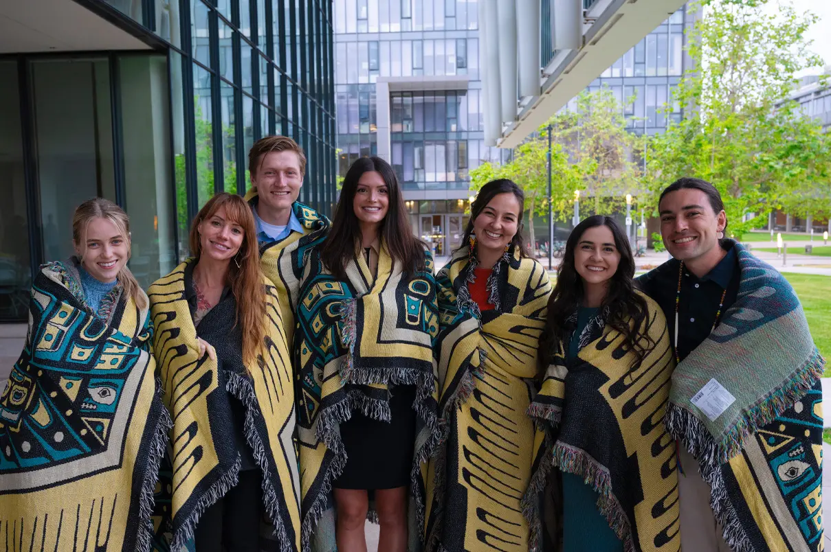 Group of seven Native American students smiling while wrapped in their blankets of knowledge