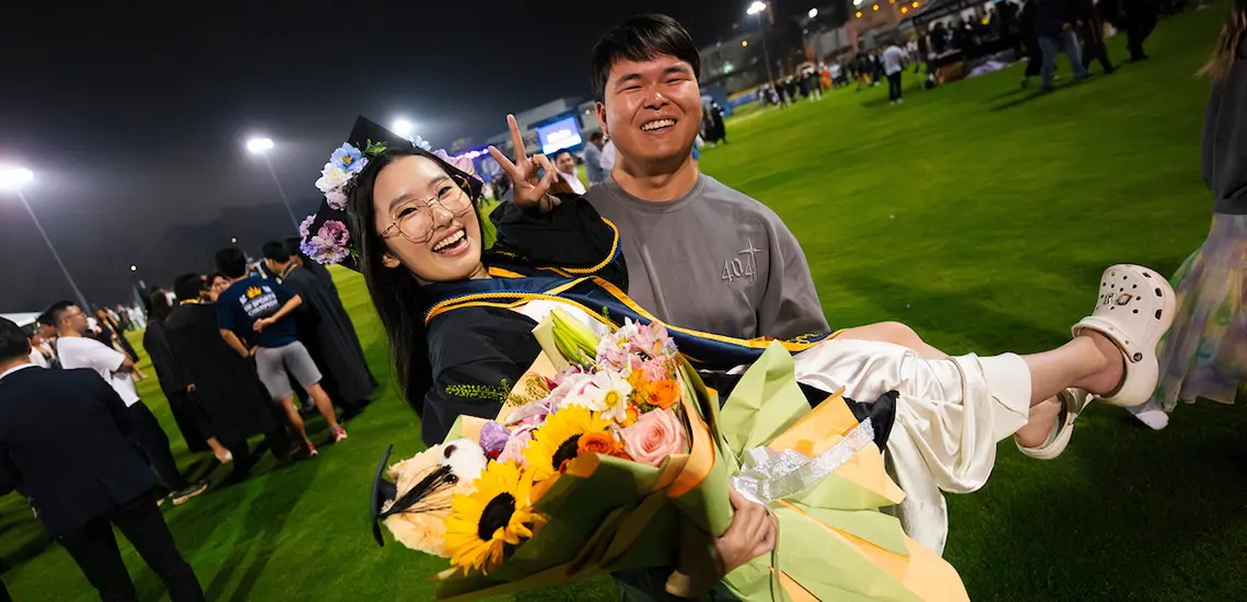 Person holds a graduate who is holding flowers