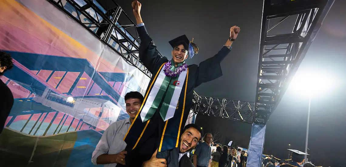 Two people hold a graduate in the air