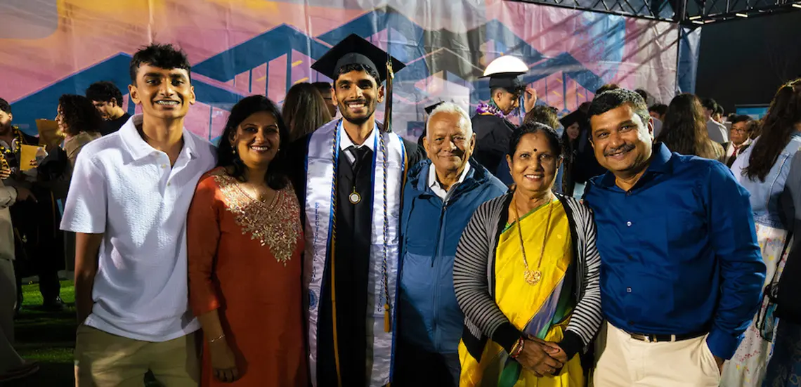 Graduate poses with parents, grandparents and sibling