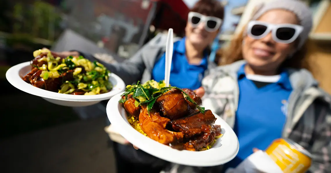 Two attendees hold out plates of food