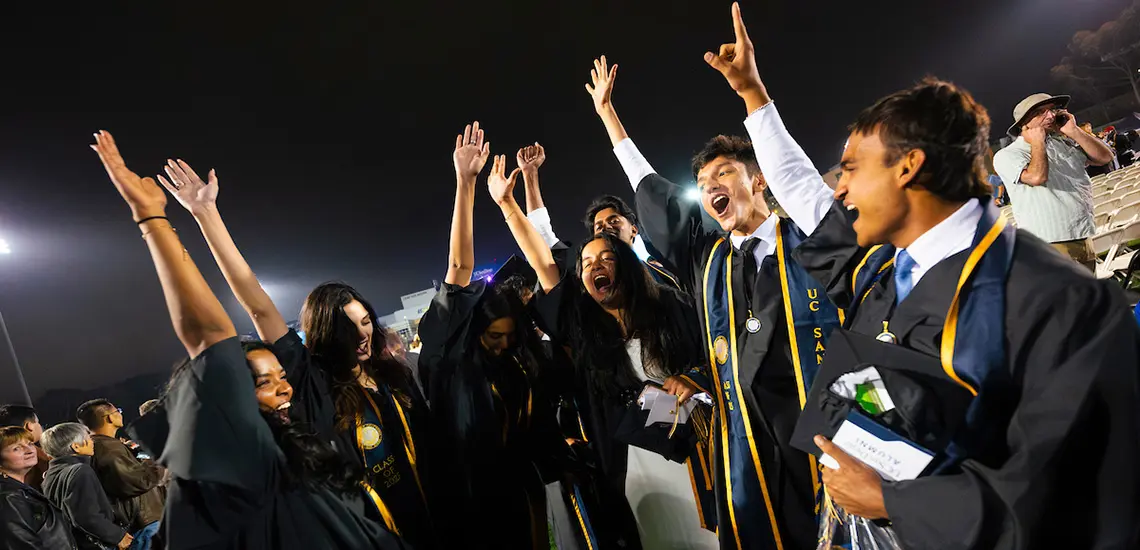 Graduates celebrate with arms in air