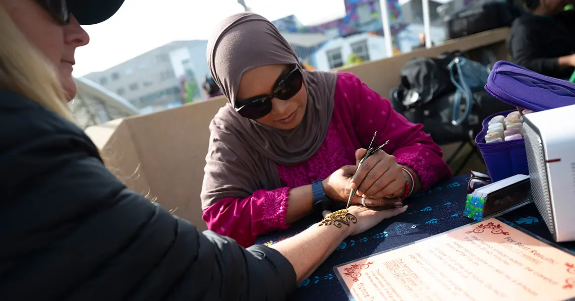 Henna artist draws design on person's hand