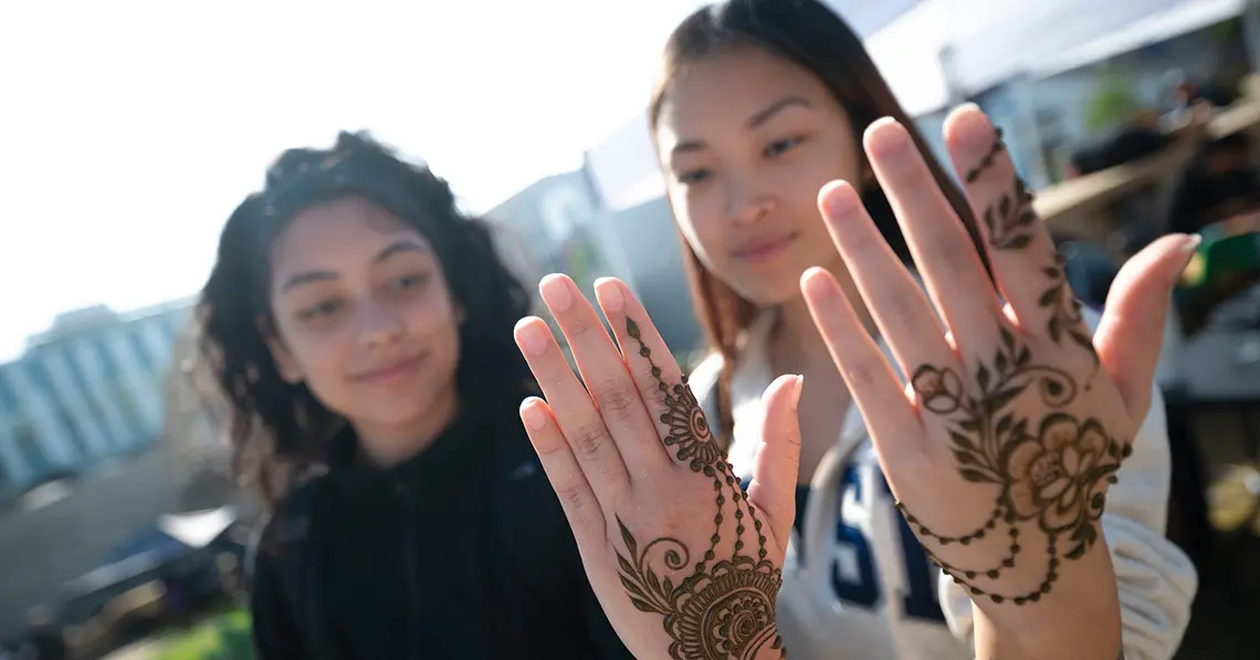 Two people hold up hands showing henna art