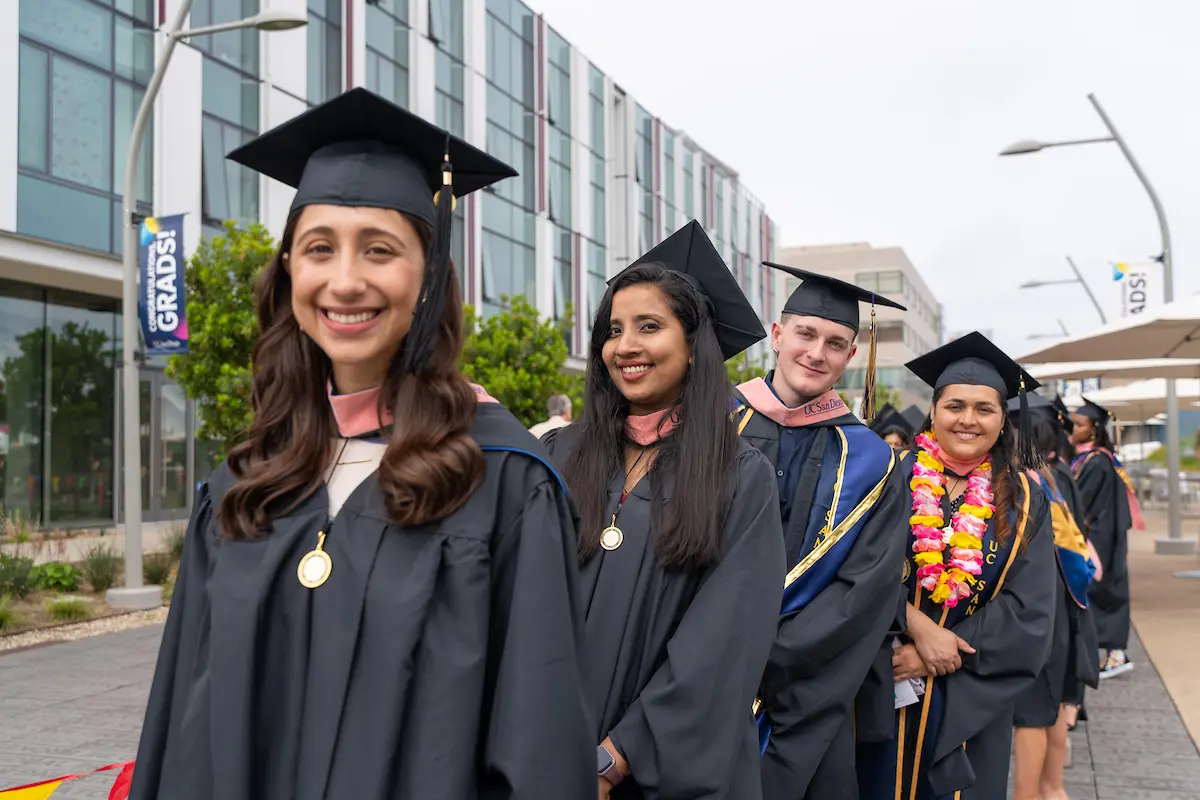 Photo of Master of Public Health Students standing in line waiting to process toward graduation. They are wearing graduation regalia.