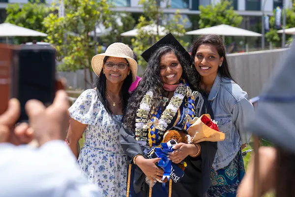 Master of Public Health graduate with family. The graduate is wearing traditional graduation regalia.