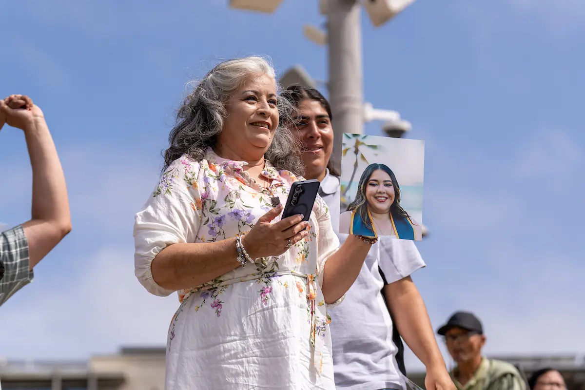Photo of a parent/guardian holding a photo of a graduate.