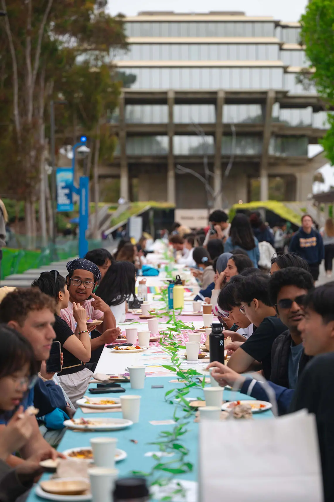 Community members gather around long table in front of Geisel Library