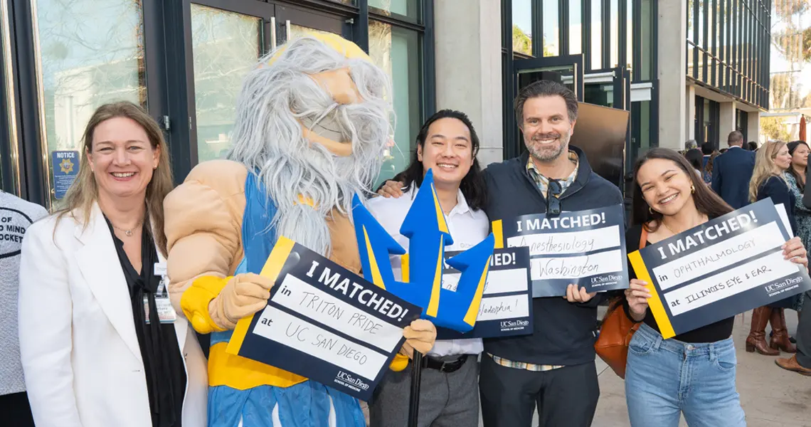 Dean Barbara Jung, King Triton and three medical students with their match day signs