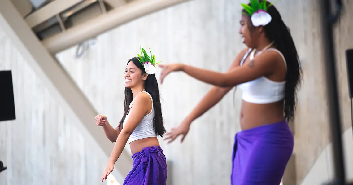 Two dancers from Polynesian Dance Club perform on stage