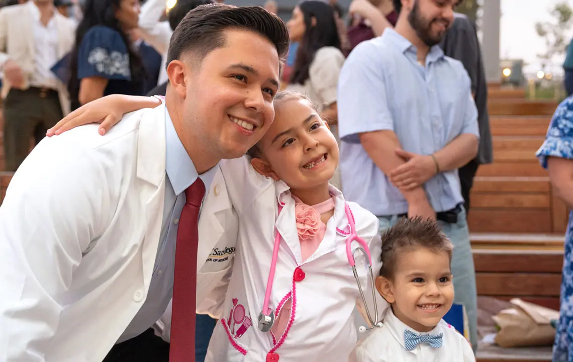 Male medical student posing and smiling with his two young children.