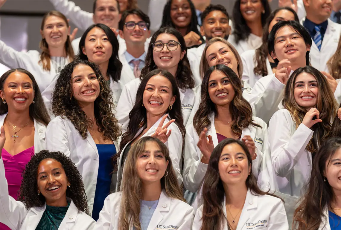 group photo of smiling students in white coats