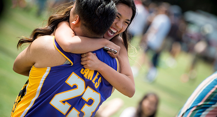 Two students hug excitedly at a UC San Diego concert outdoors