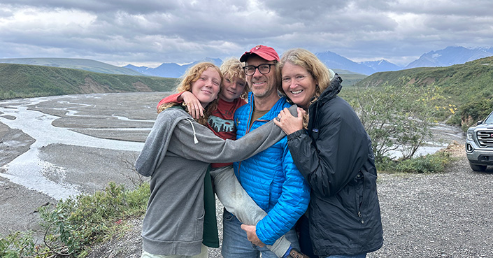 Family of four in front of scenic mountain view