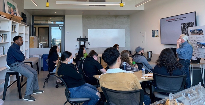 Small group of students sitting in a classroom listening to a lecture in the Design Lab.