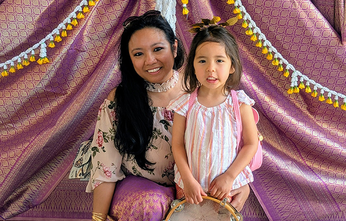 A mom posing and smiling with her daughter.