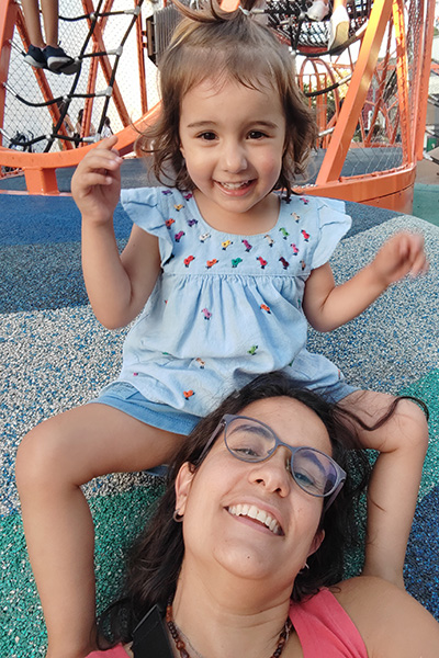A student-mom and her daughter smiling at the playground.