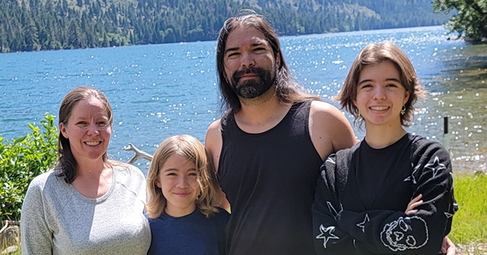 Family of four standing in front of a lake
