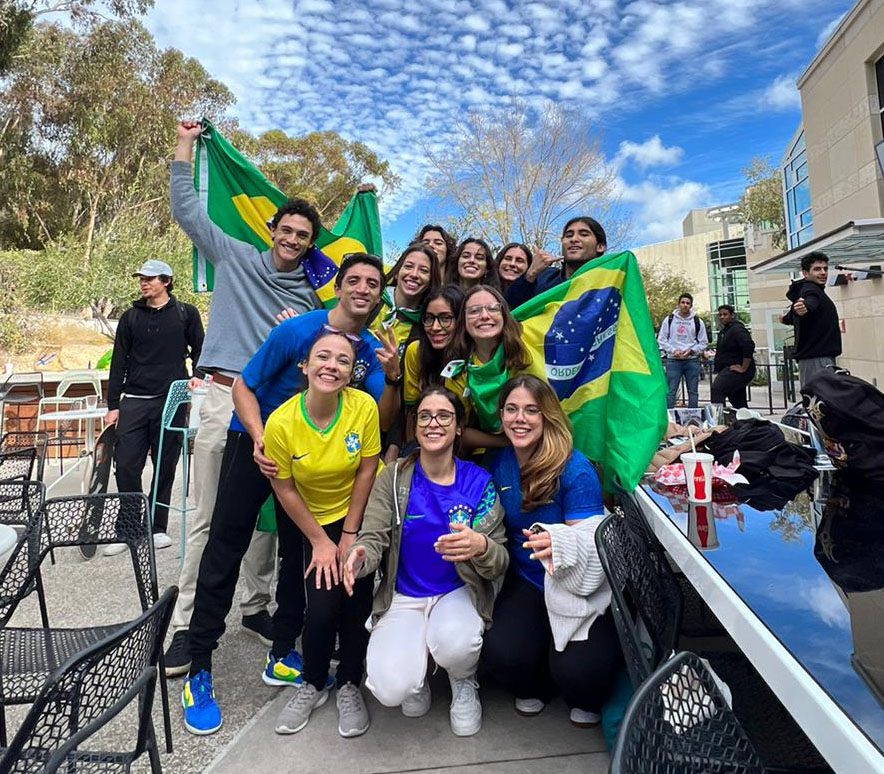 A group of students posing for a picture. Some are wearing clothes and holding up flags representing Brazil. Photo courtesy of Peixoto.