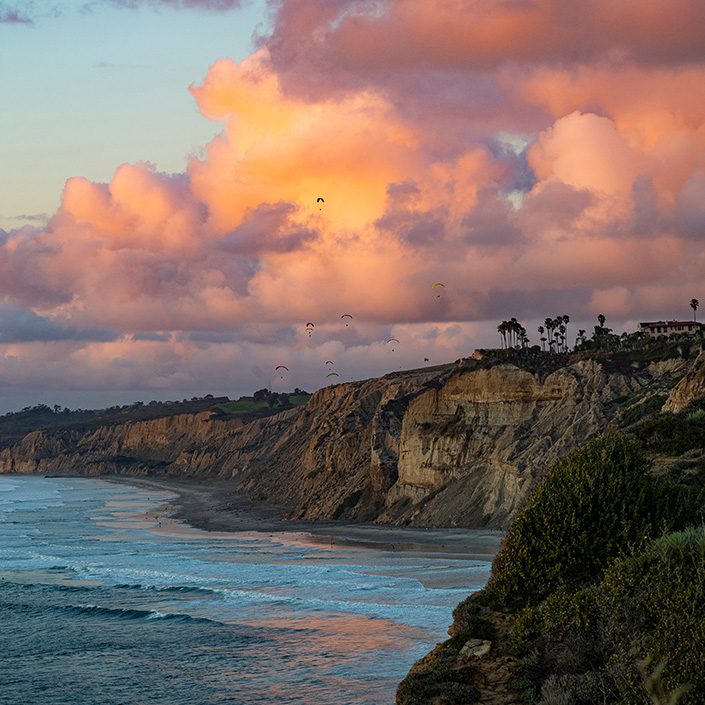 Black's Beach cliffs with paragliders above and ocean below