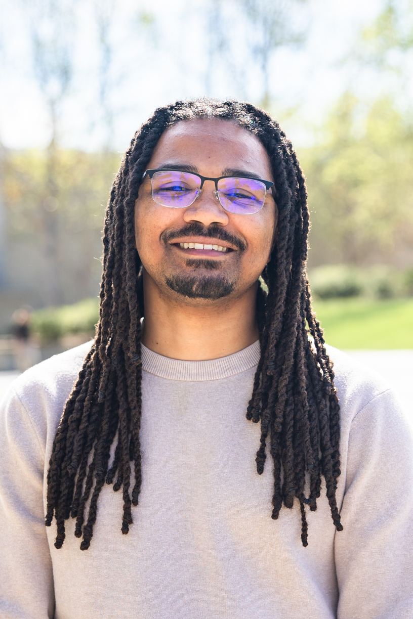 Smiling person wearing glasses and a tan sweater