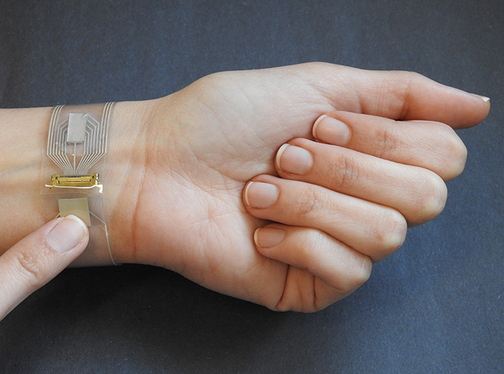 Clear band with small electronics worn on a person's wrist.