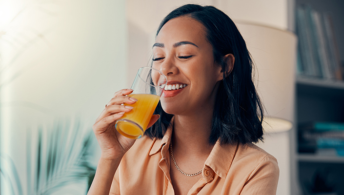 Woman drinks orange liquid from a glass