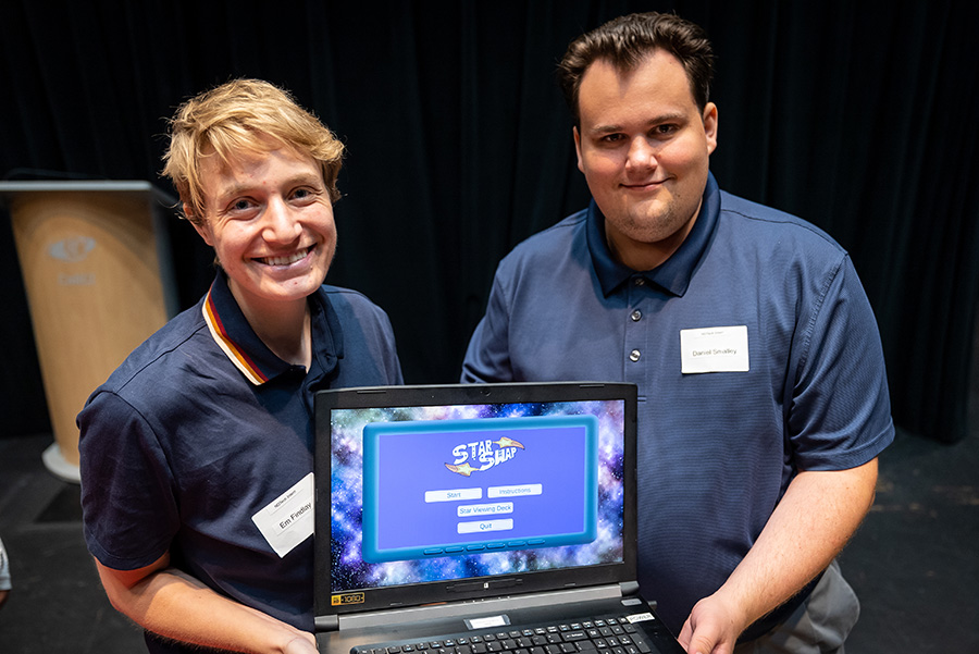 Designer Em Findlay and project manager Daniel Smalley hold a laptop showing Star Swap