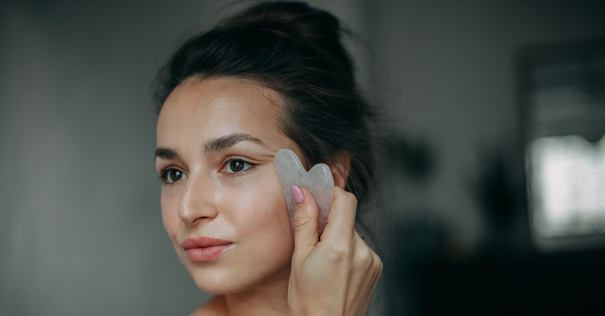 Person holds gua she device up to face
