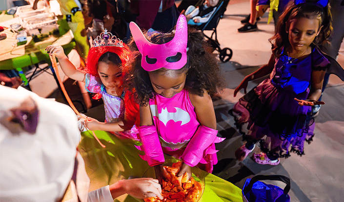 Children dressed in costume getting treats from a bowl