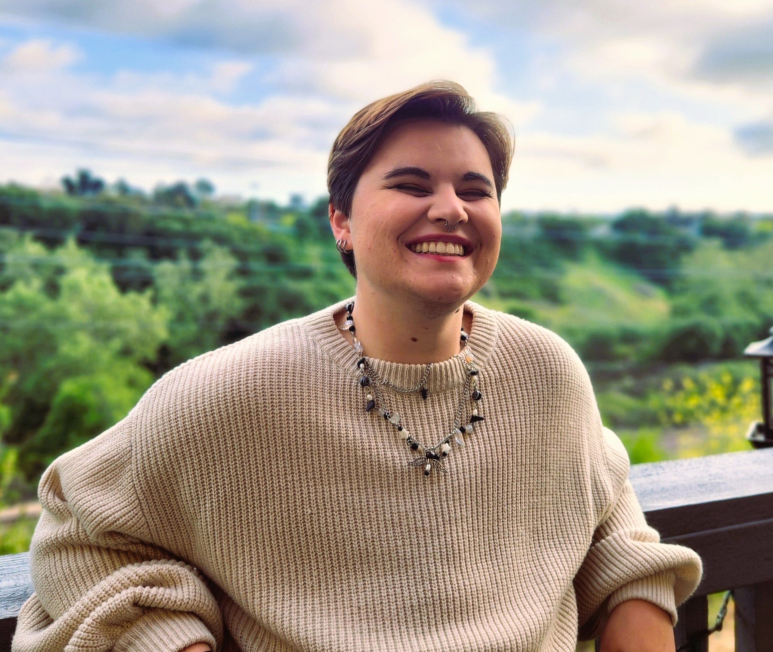 Student wearing tan sweater smiles at the camera