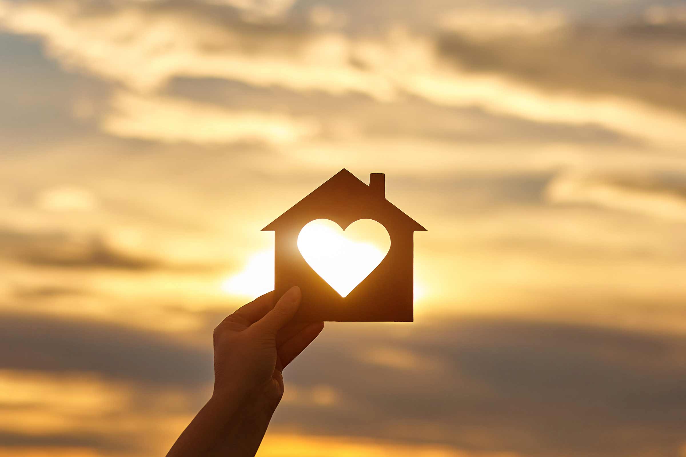 Hand holding silhouette of home with heart