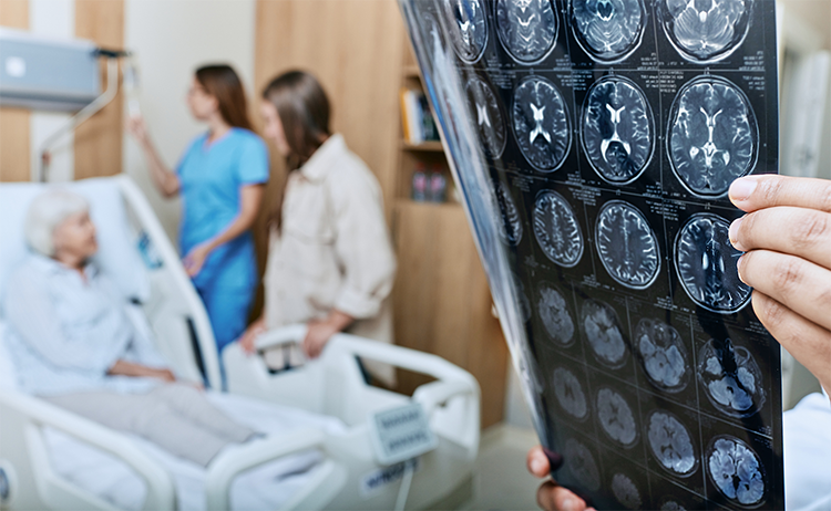 Photo of MRI scan of brain while patient is in the background in bed with nurse.