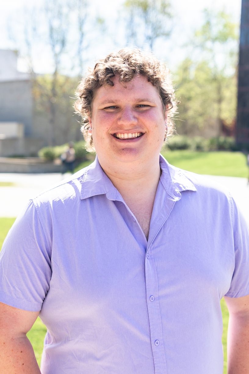 person smiling at the camera wearing a purple shirt