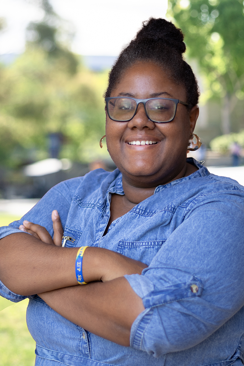 person smiling at camera wearing a denim shirt