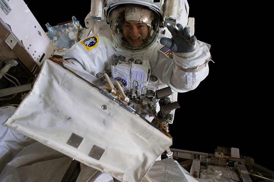 Jessica Meir waves at the camera during a spacewalk.