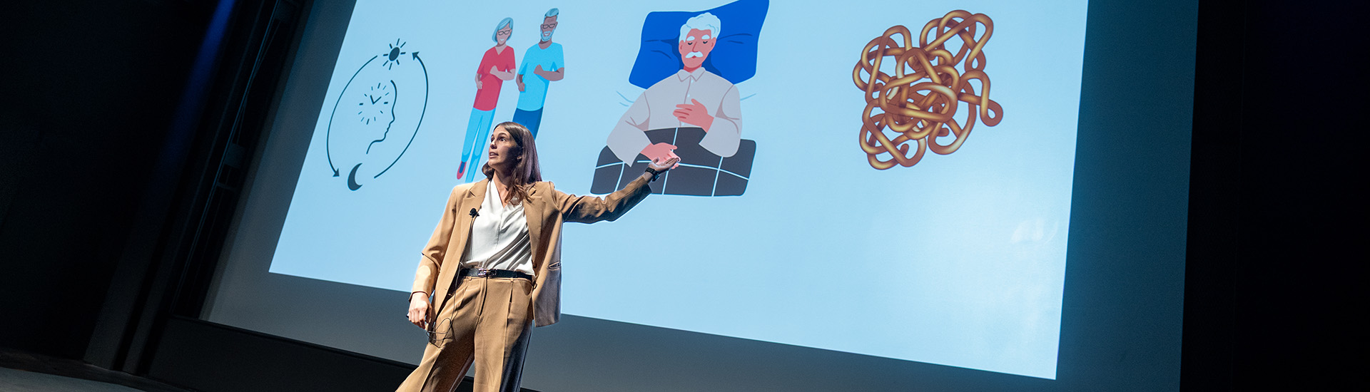 Person on stage gestures toward slide on screen