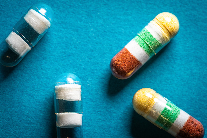 Capsules with white stripes and red, green and yellow colors against a blue background.