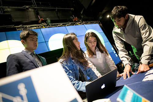 students conversing around a computer