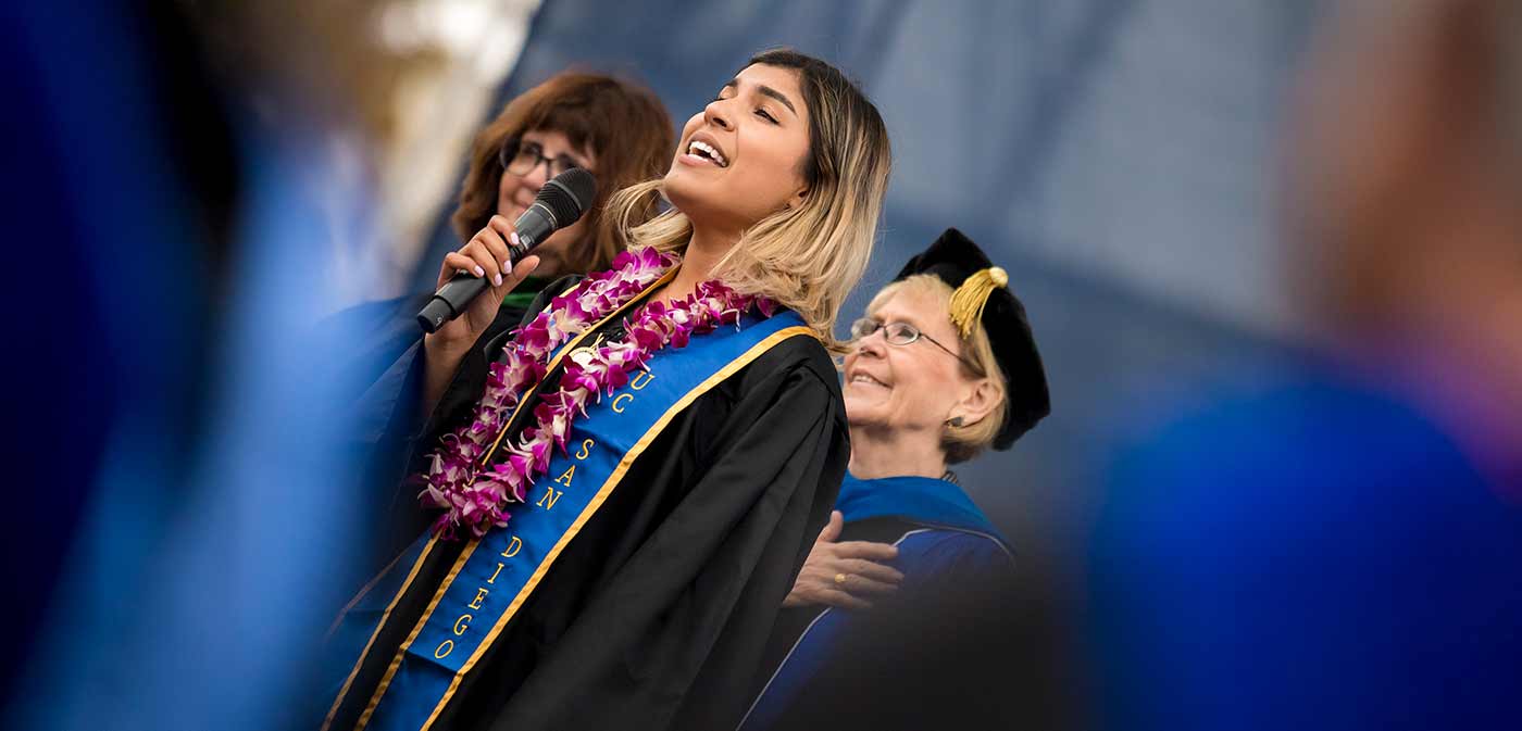 student singing the national anthem at past commencement.