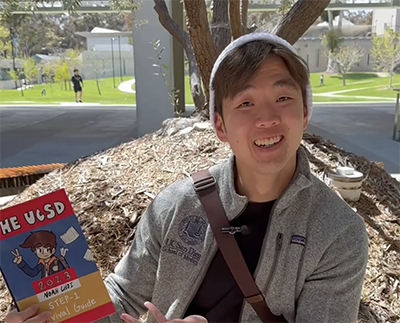 Medical Student Noah Choi is shown smiling holding a copy of the comic book he created.