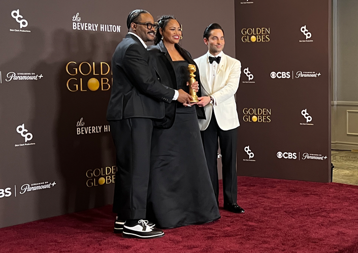 A large group in formal attire gather to accept a movie industry award