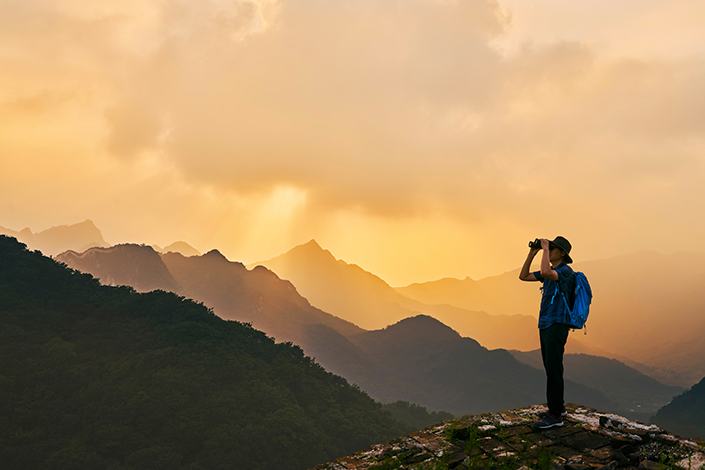 A man standing on a mountain with binoculars