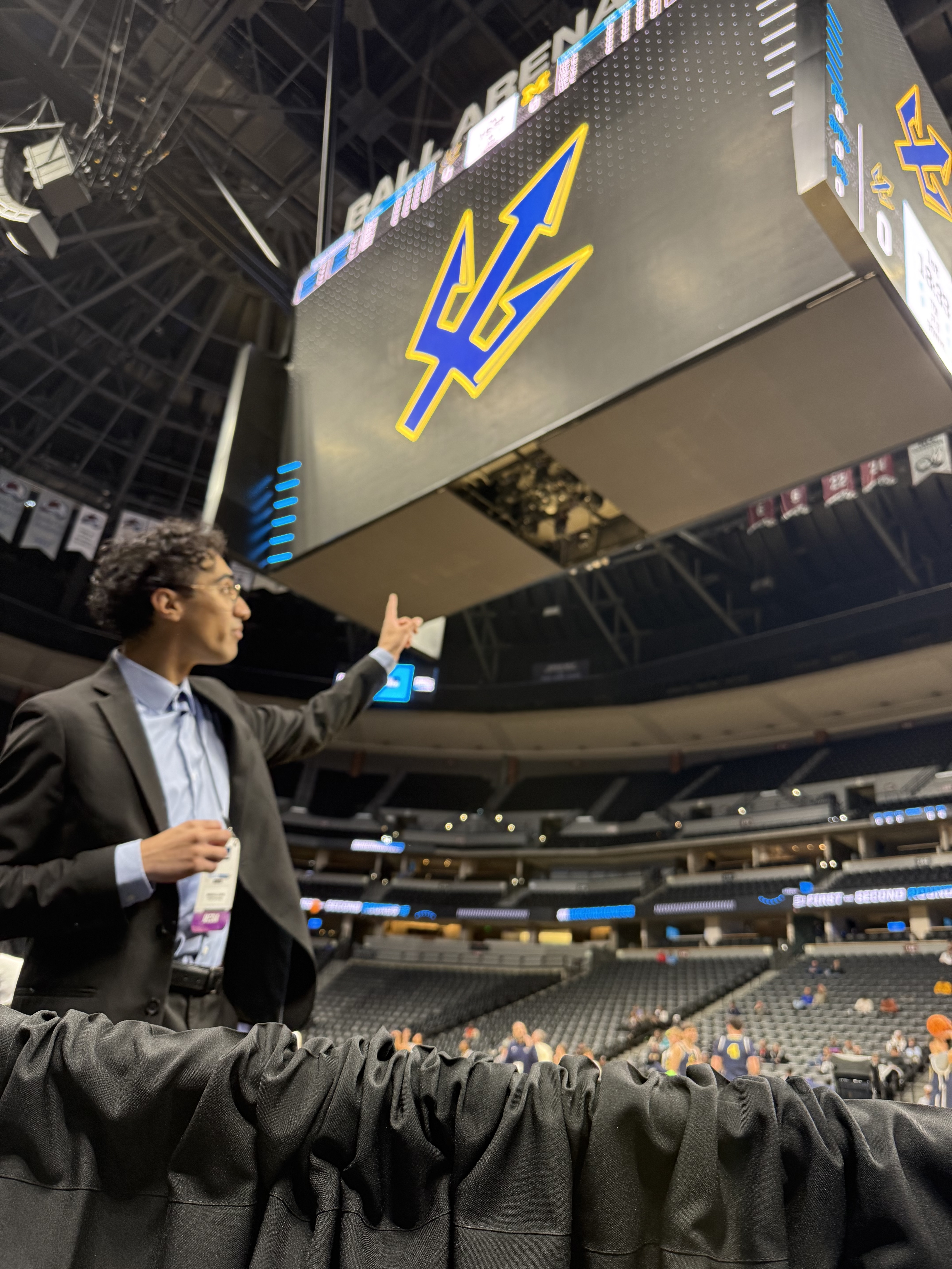 Student in suit points at logo on jumbotron